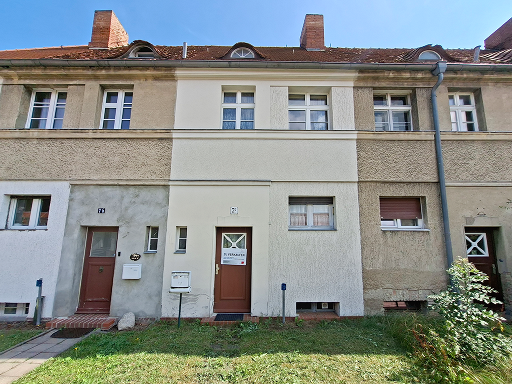 Frontansicht eines 2-stöckigen Reihenhauses. Das Mittelhaus hat eine weiße Fassade. 