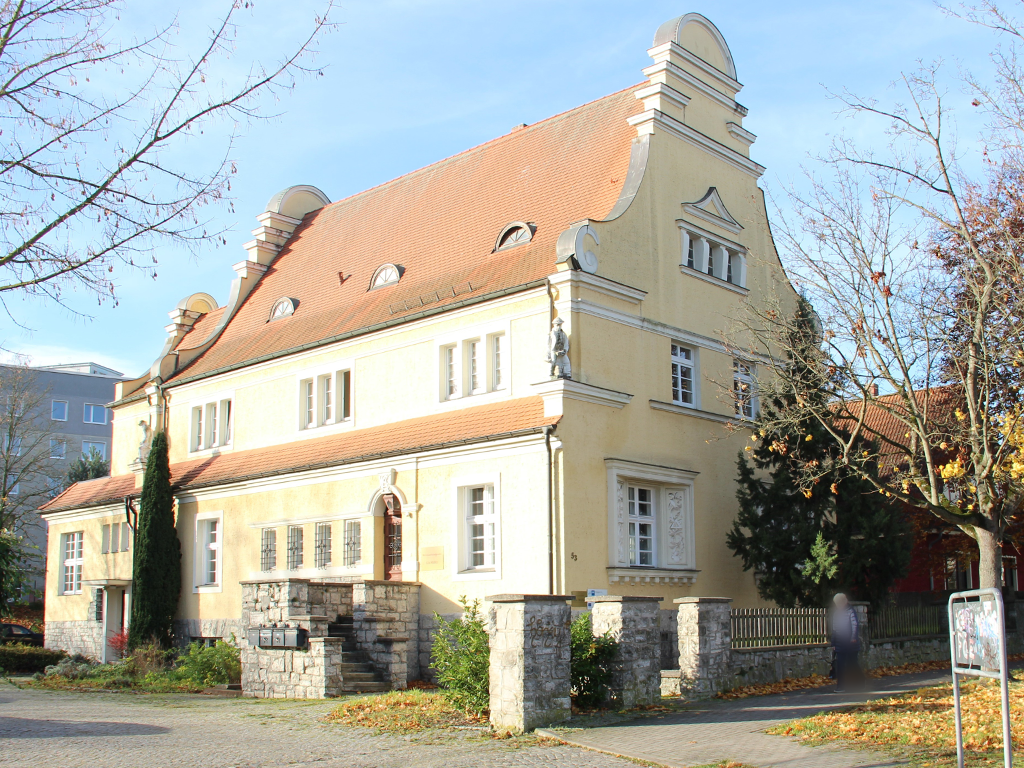Außenansicht einer großen Villa mit gelbem Putz und Ziergieblen.