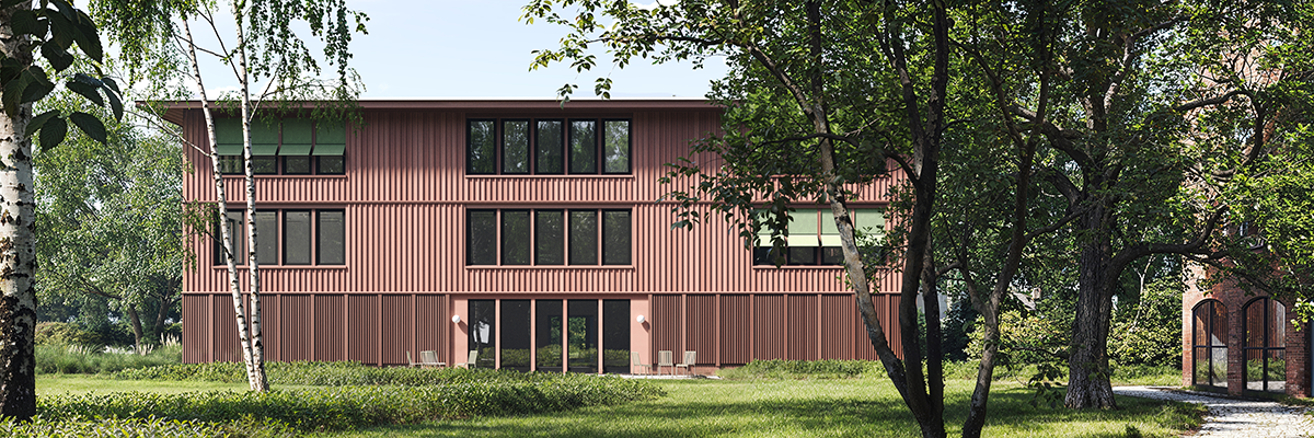 Bild: Frontansicht des neuen Gebädues mit Erdgeschoss und zwei Etage. Fassade besteht aus roten Lamellen und großen Fensterfronten. Das Gebäude ist umgeben mit viel grün und Baumbestand.