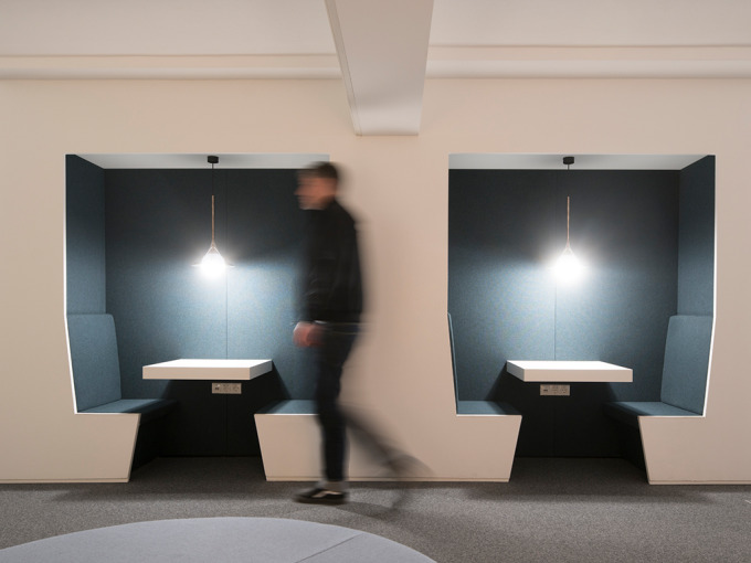 Zwei hell ausgeleuchtete Sitznischen mit dunklem Stoff bezogen. 