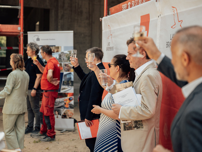 Gäste erheben das Glas zum Richtspruch.