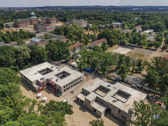 Luftaufnahme von zwei Rohbauten mit Innenhöfen. Im Hintergrund ist die historische Schlossanlage zu sehen.