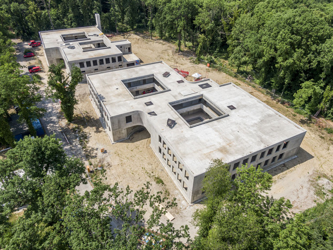 Luftaufnahme von zwei Rohbauten mit Innenhöfen. Umgeben sind die Gebäude von Bäumen.